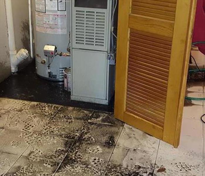 muddy sludge after flooding in basement, heater shown